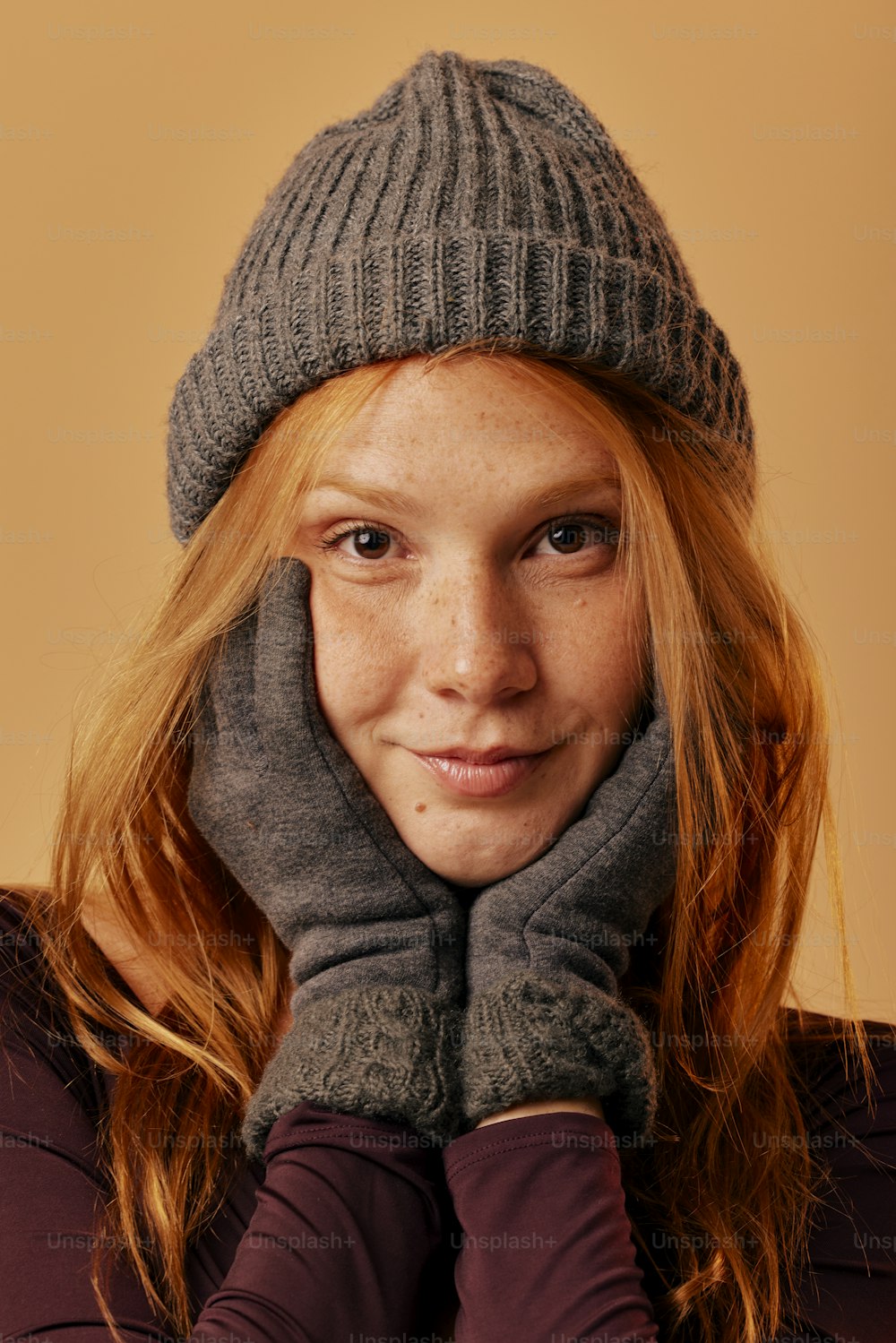 a woman with red hair wearing a gray hat and gloves