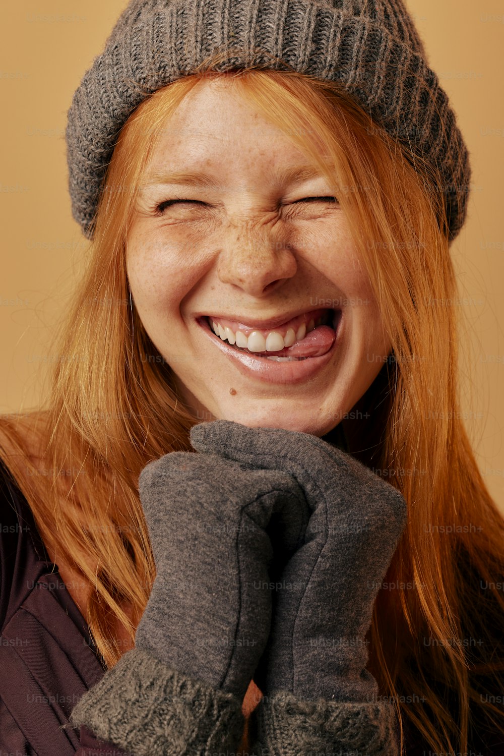 a woman with red hair wearing a gray hat and mittens