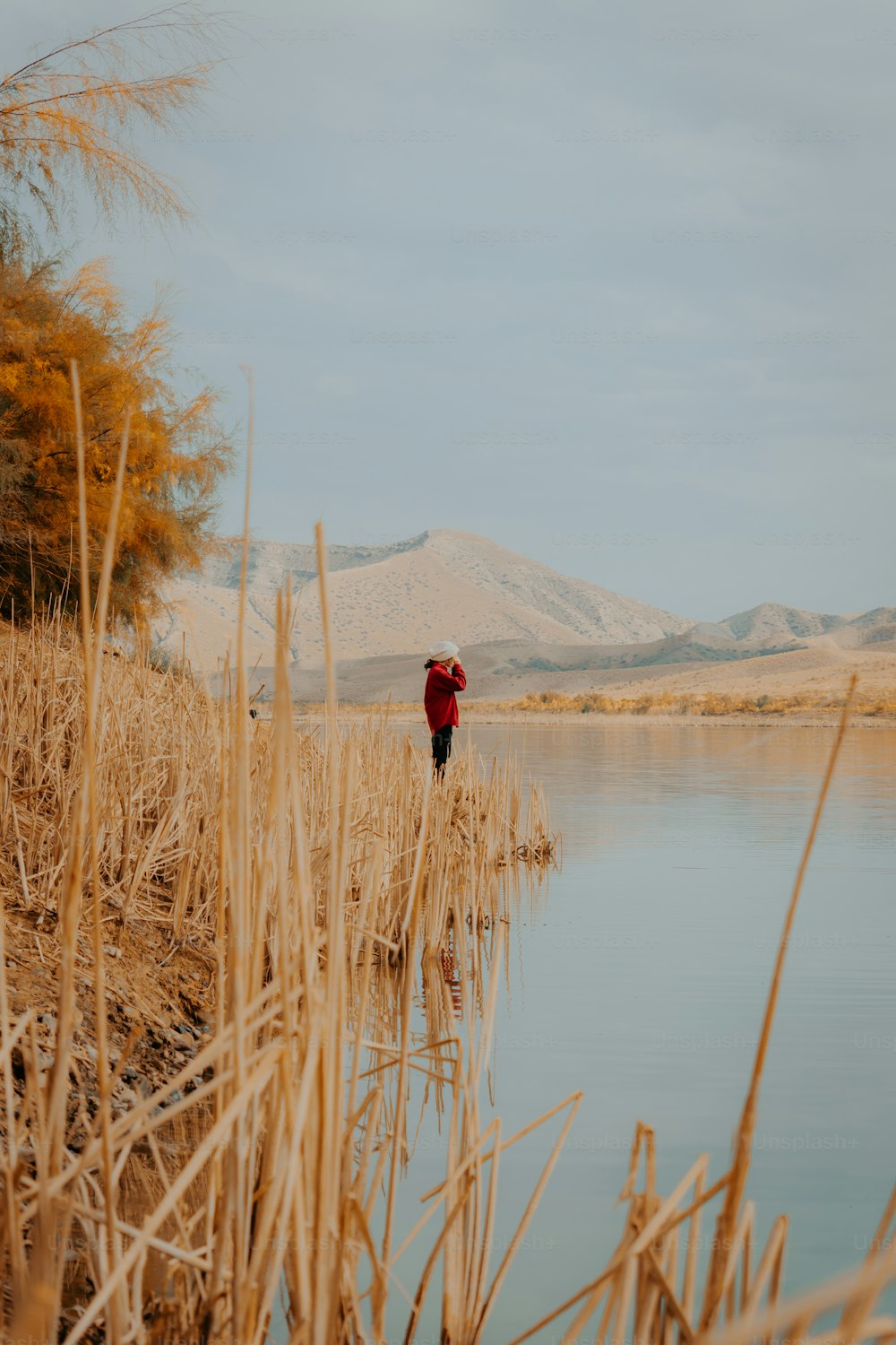 a person in a red jacket standing by a body of water
