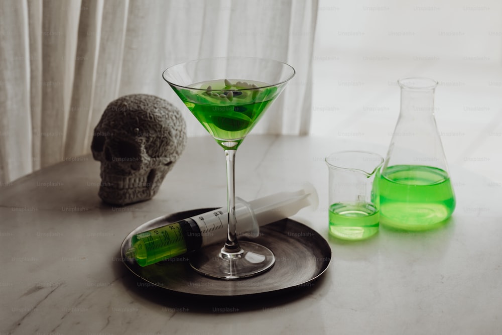 a glass of green liquid next to a bottle of liquid