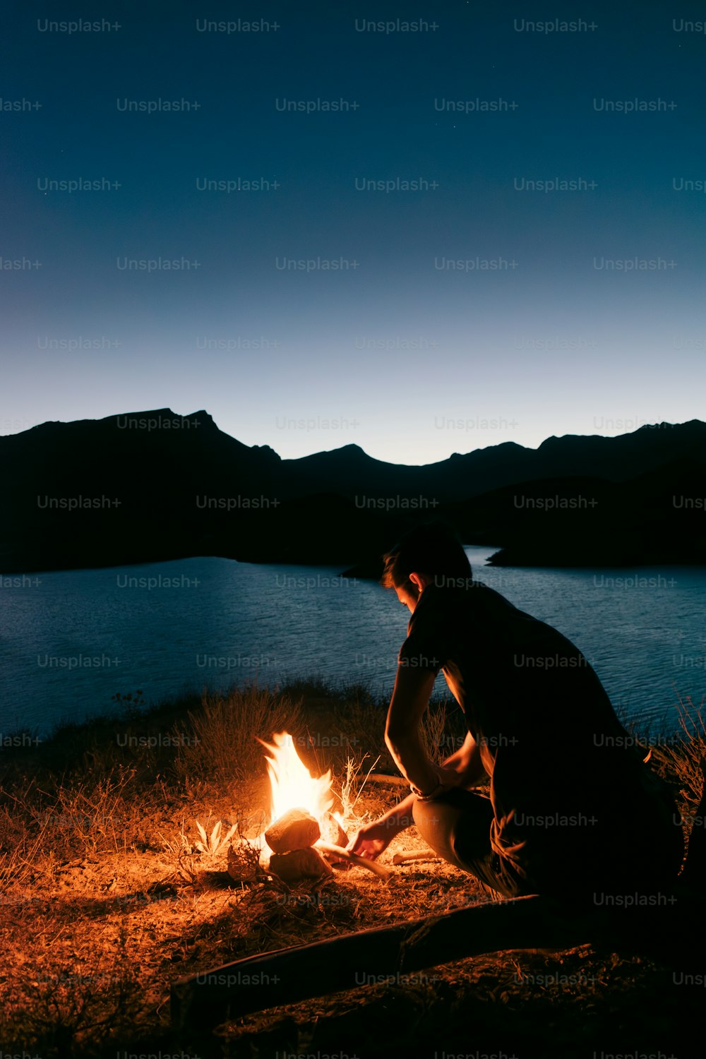 um homem sentado em frente a uma fogueira à noite