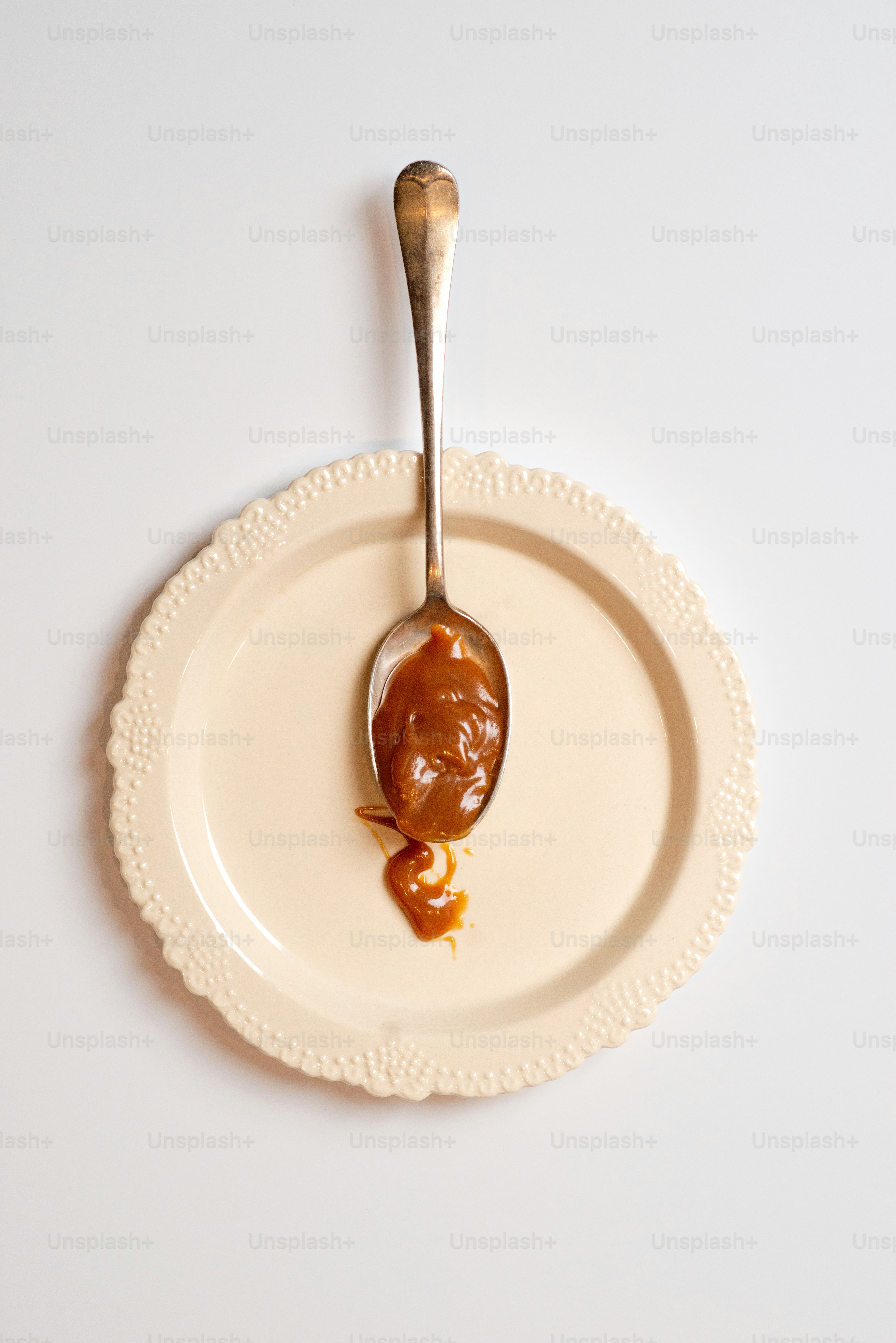 una cuchara llena de mantequilla de maní encima de un plato blanco