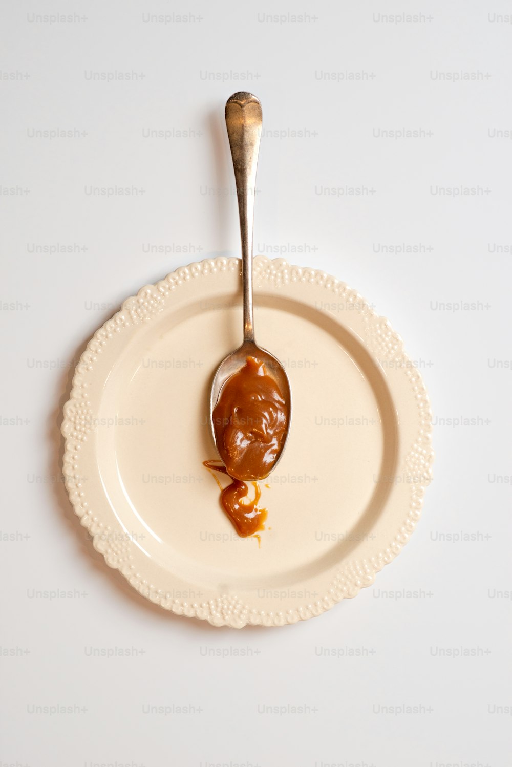 a spoon filled with peanut butter on top of a white plate