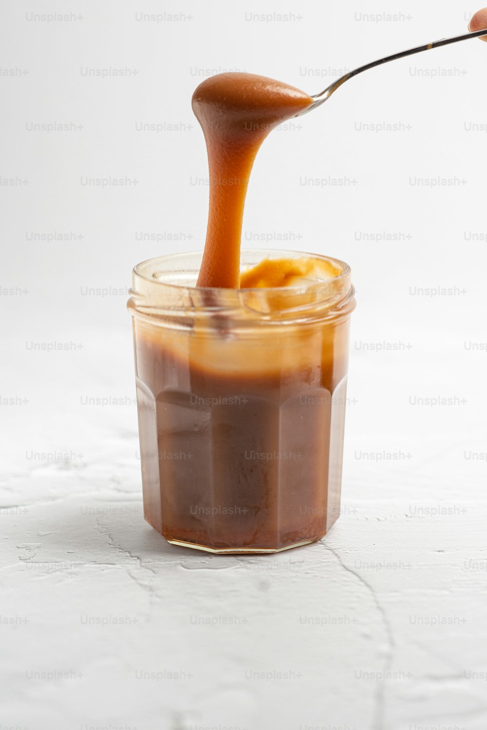 a spoon full of caramel sauce in a jar