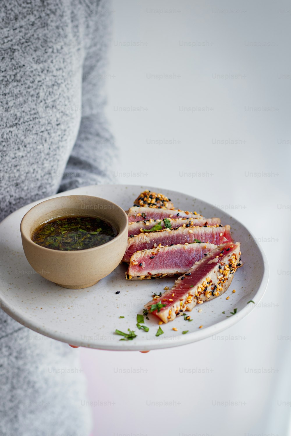 a person holding a plate with a sandwich and a bowl of soup