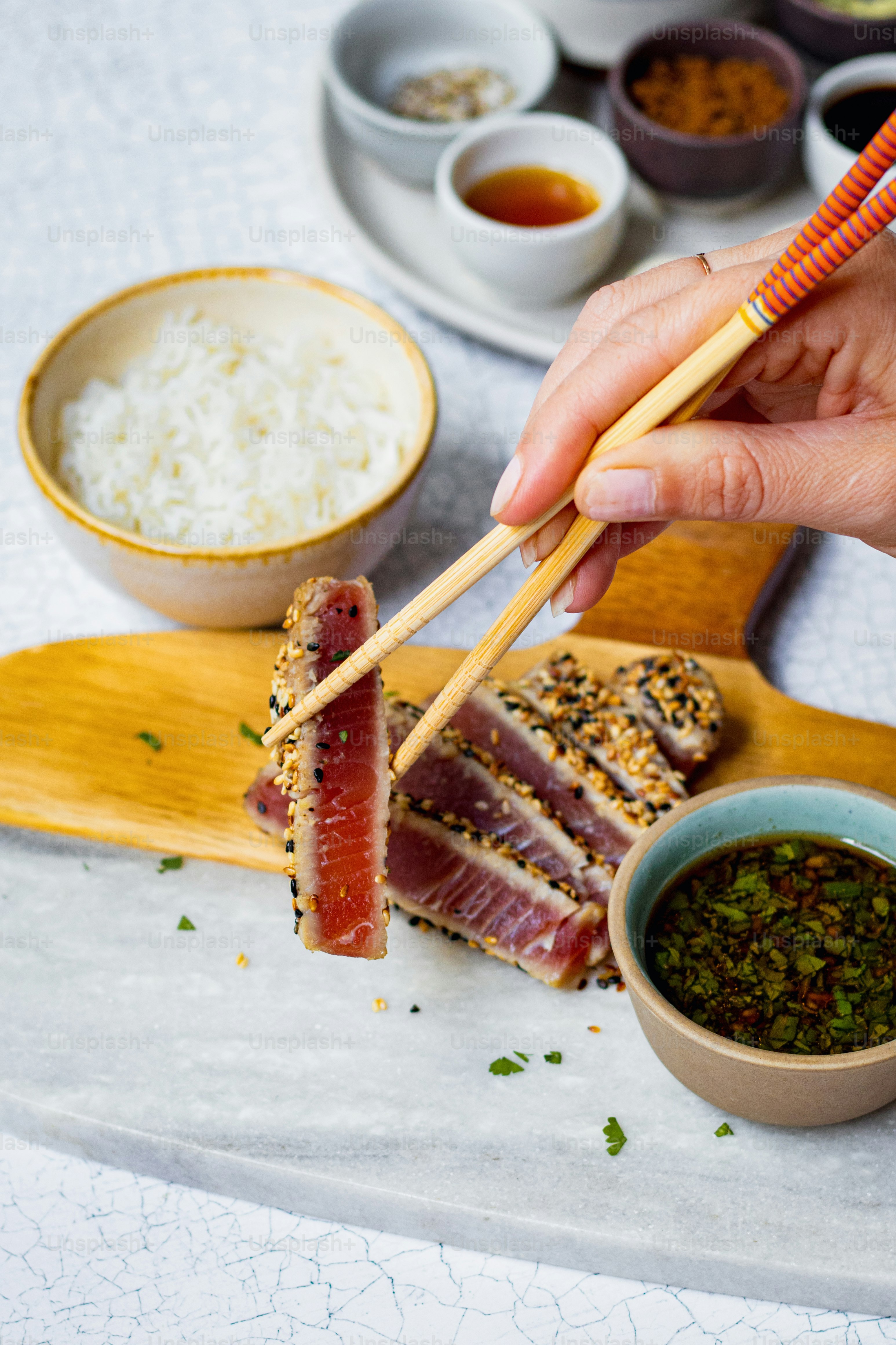 a person holding chopsticks over a plate of food