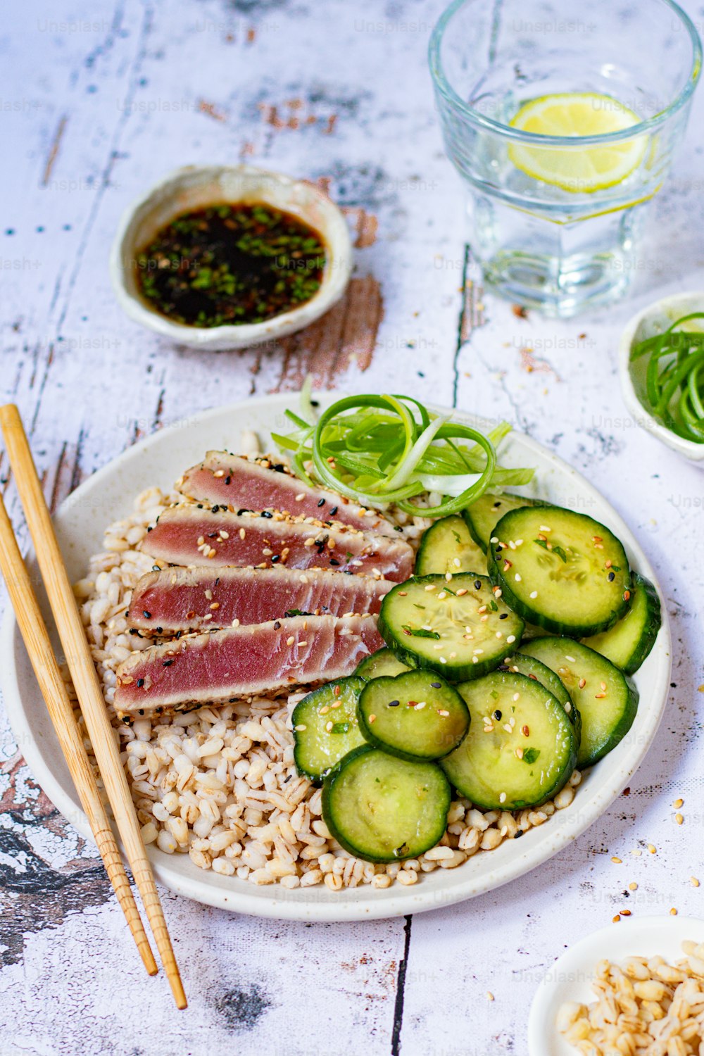 a plate of food with meat, rice, and cucumbers