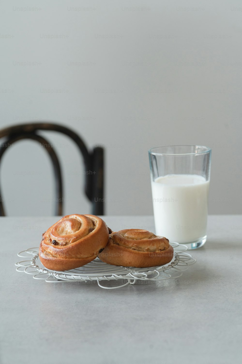 a glass of milk and two cinnamon buns on a plate