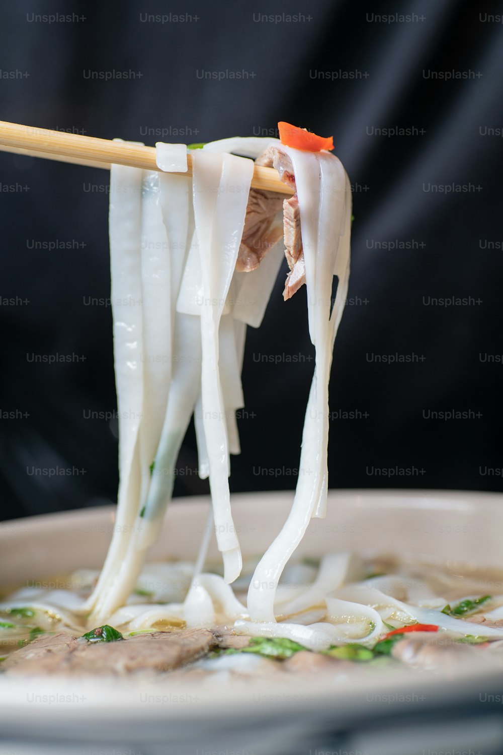 a close up of a bowl of noodles with chopsticks