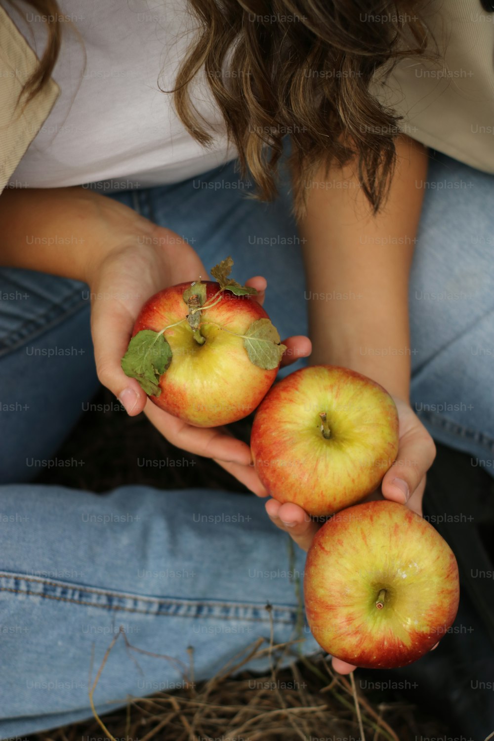 a woman holding three apples in her hands