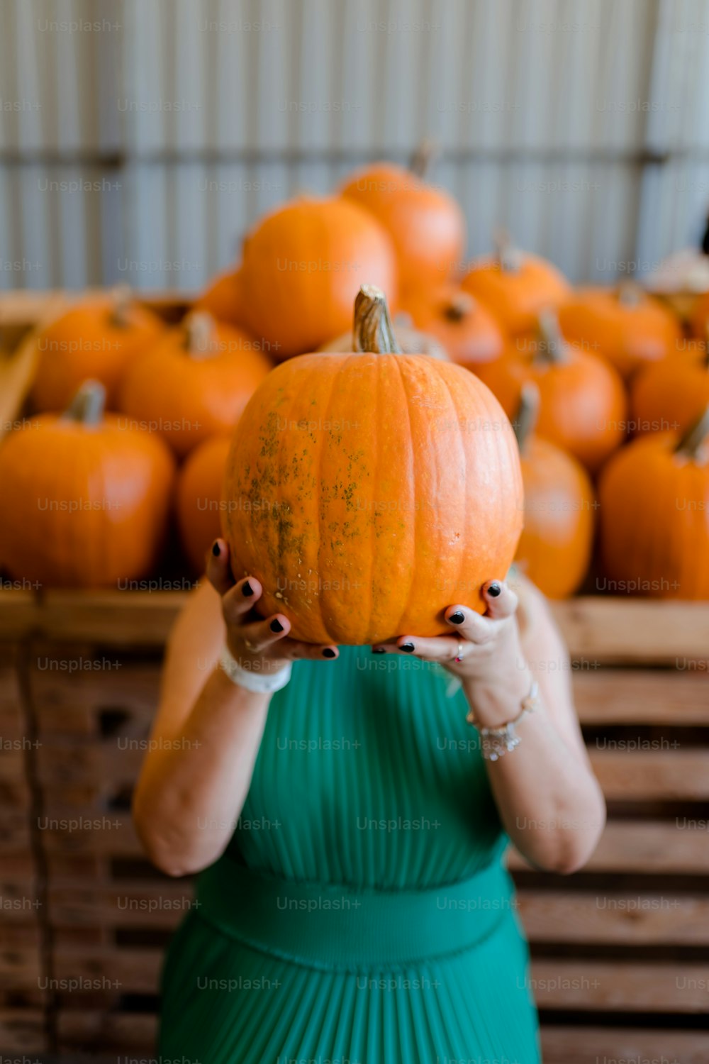 a woman in a green dress holding a pumpkin