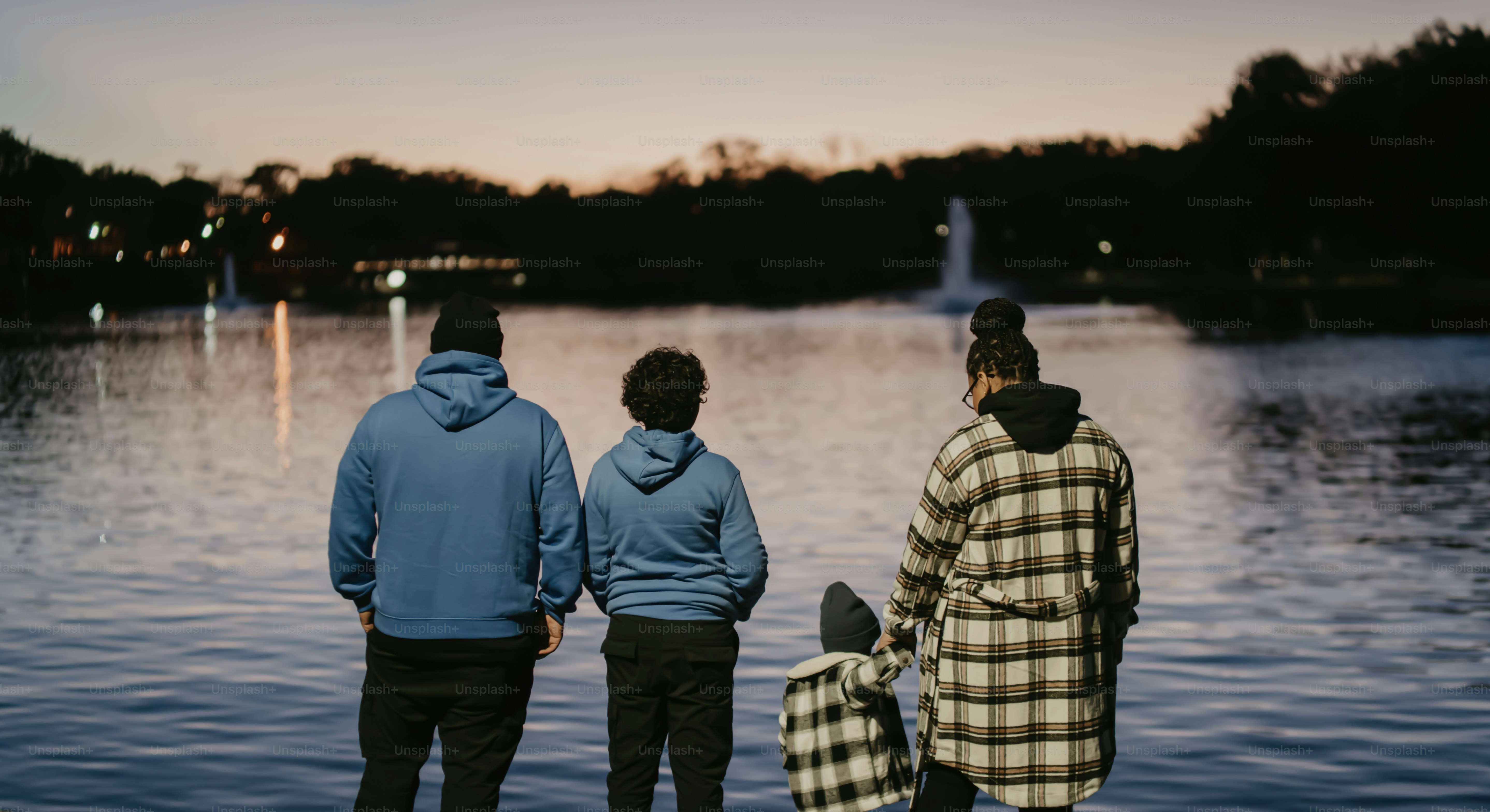 a group of three people standing next to a body of water