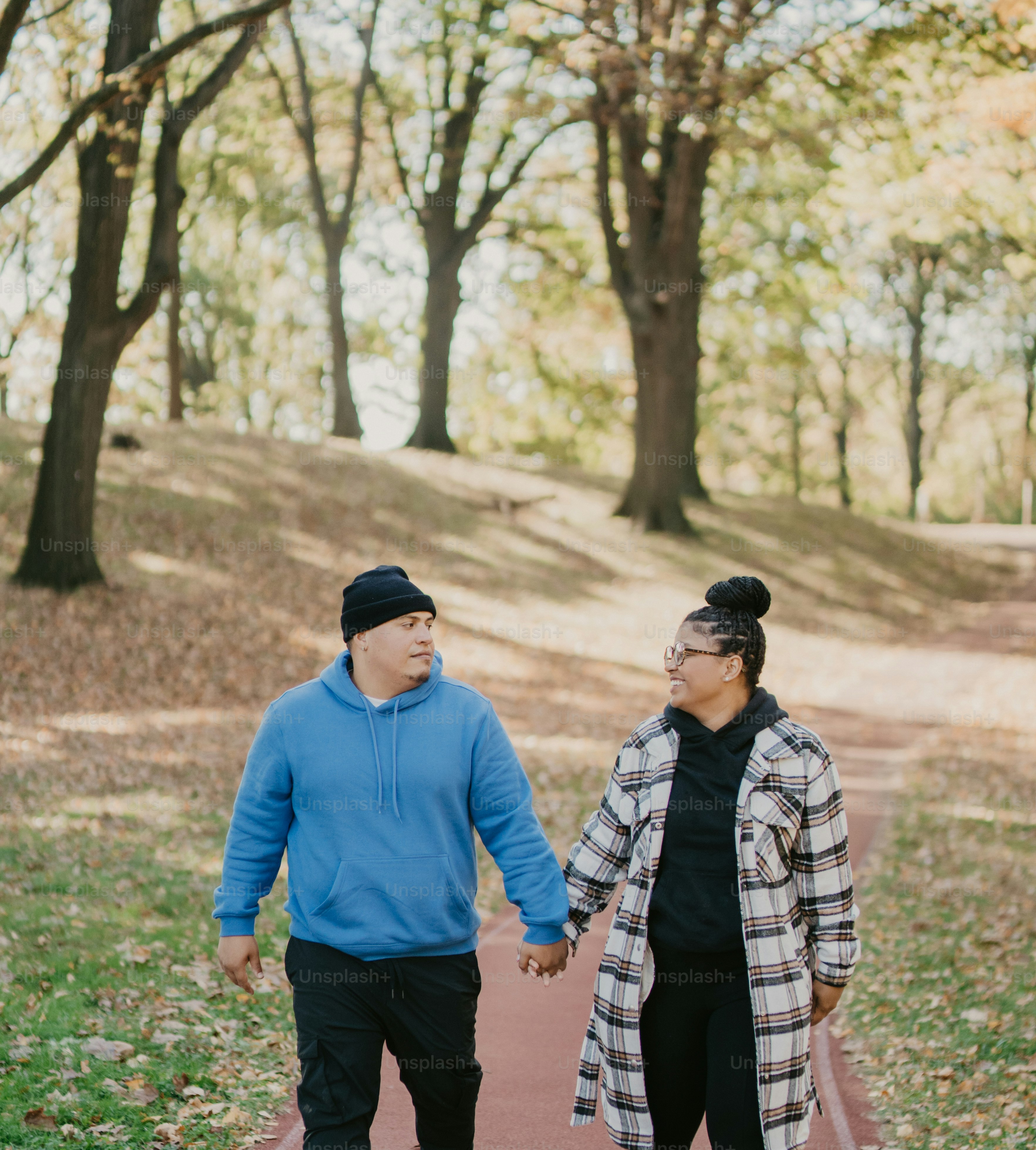 a man and woman walking down a path holding hands