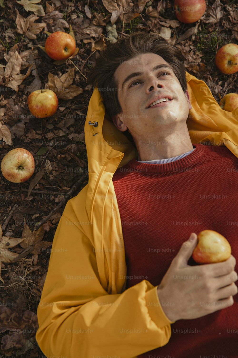 a man laying on the ground holding an apple