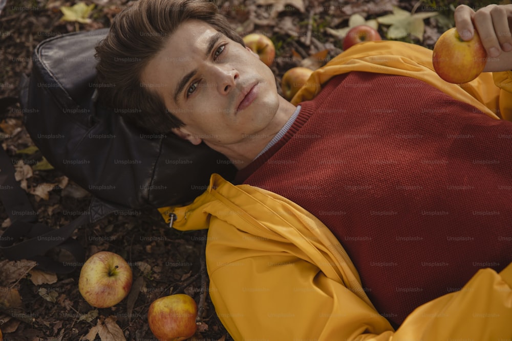 a man laying on the ground next to apples