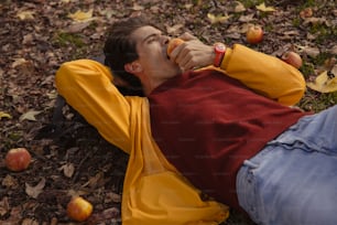 a man laying on the ground eating an apple