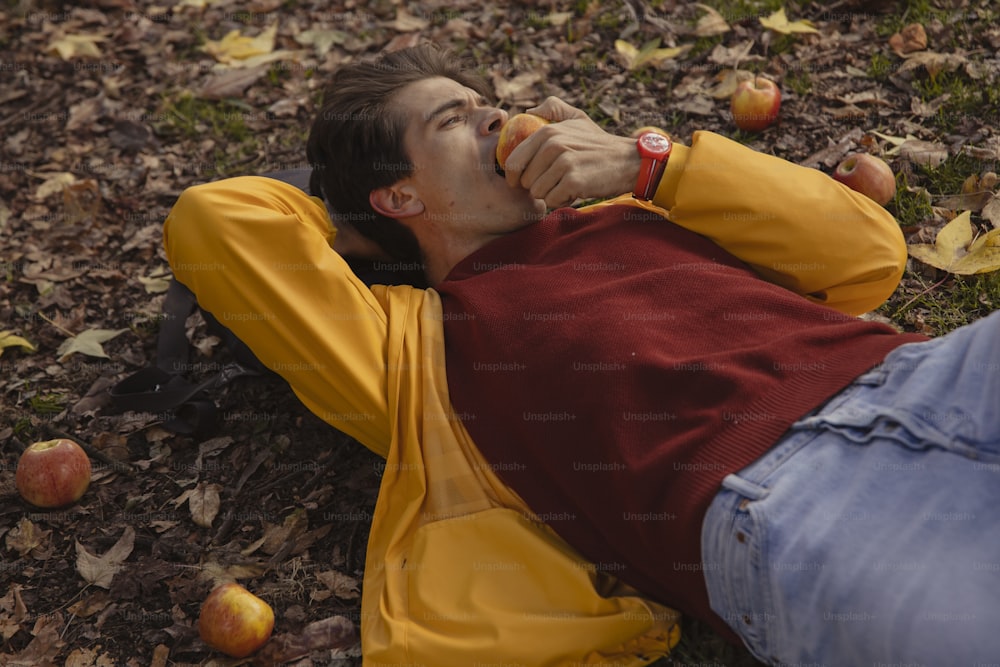 a man laying on the ground eating an apple