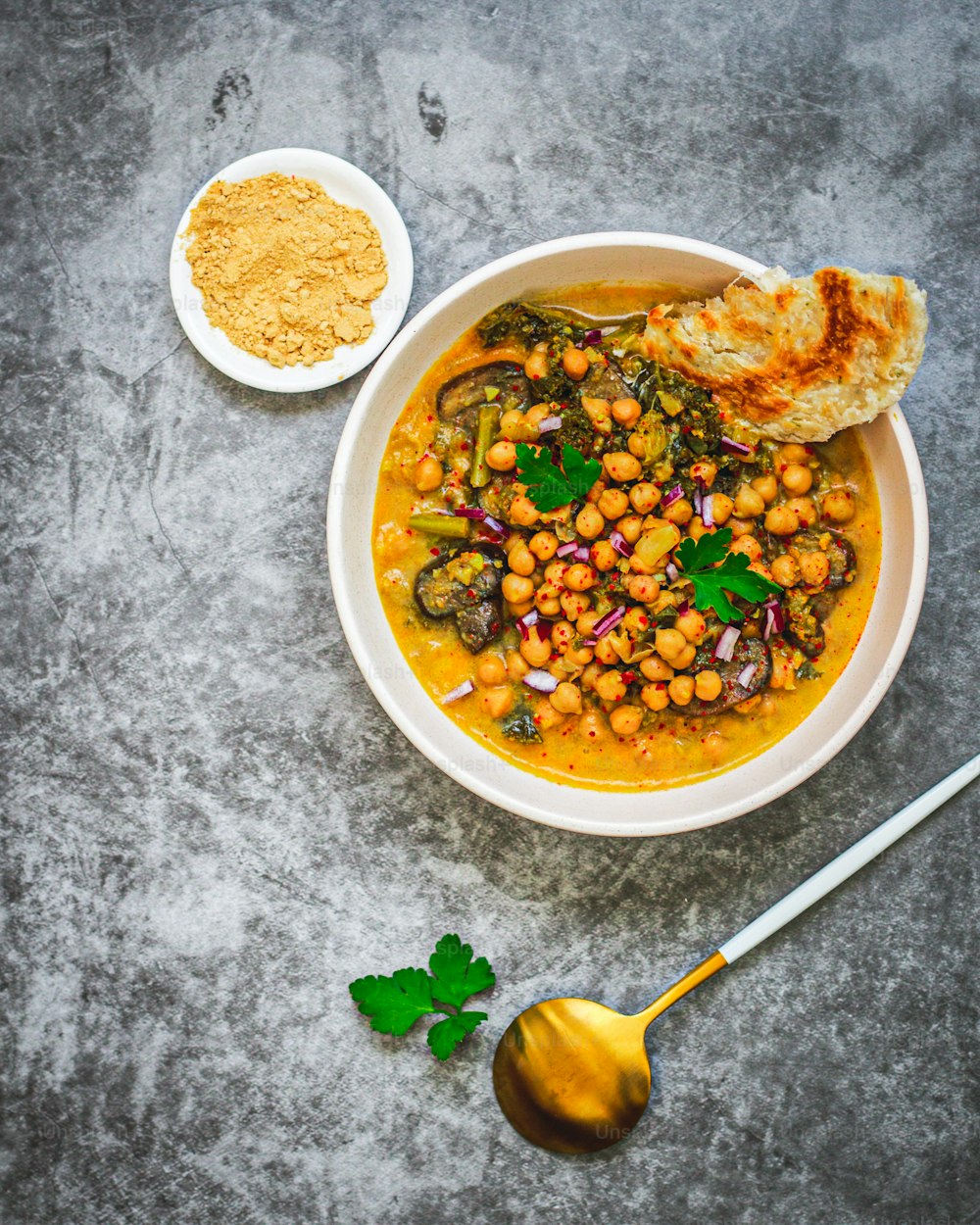 a bowl of chickpea soup with a spoon next to it