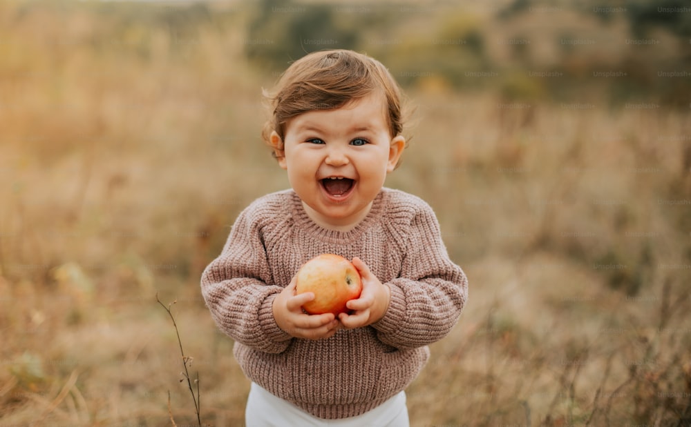 Una niña sosteniendo una manzana en un campo