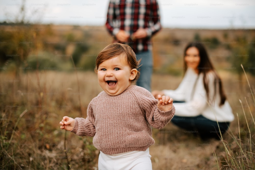 a little girl laughing in a field with a man in the background