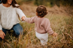 a woman holding the hand of a little girl in a field