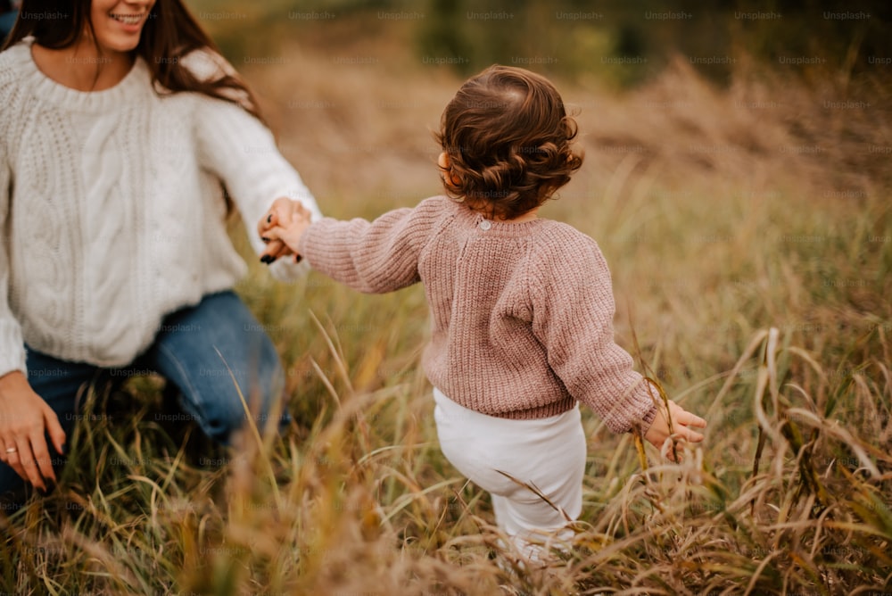 Una mujer sosteniendo la mano de una niña en un campo