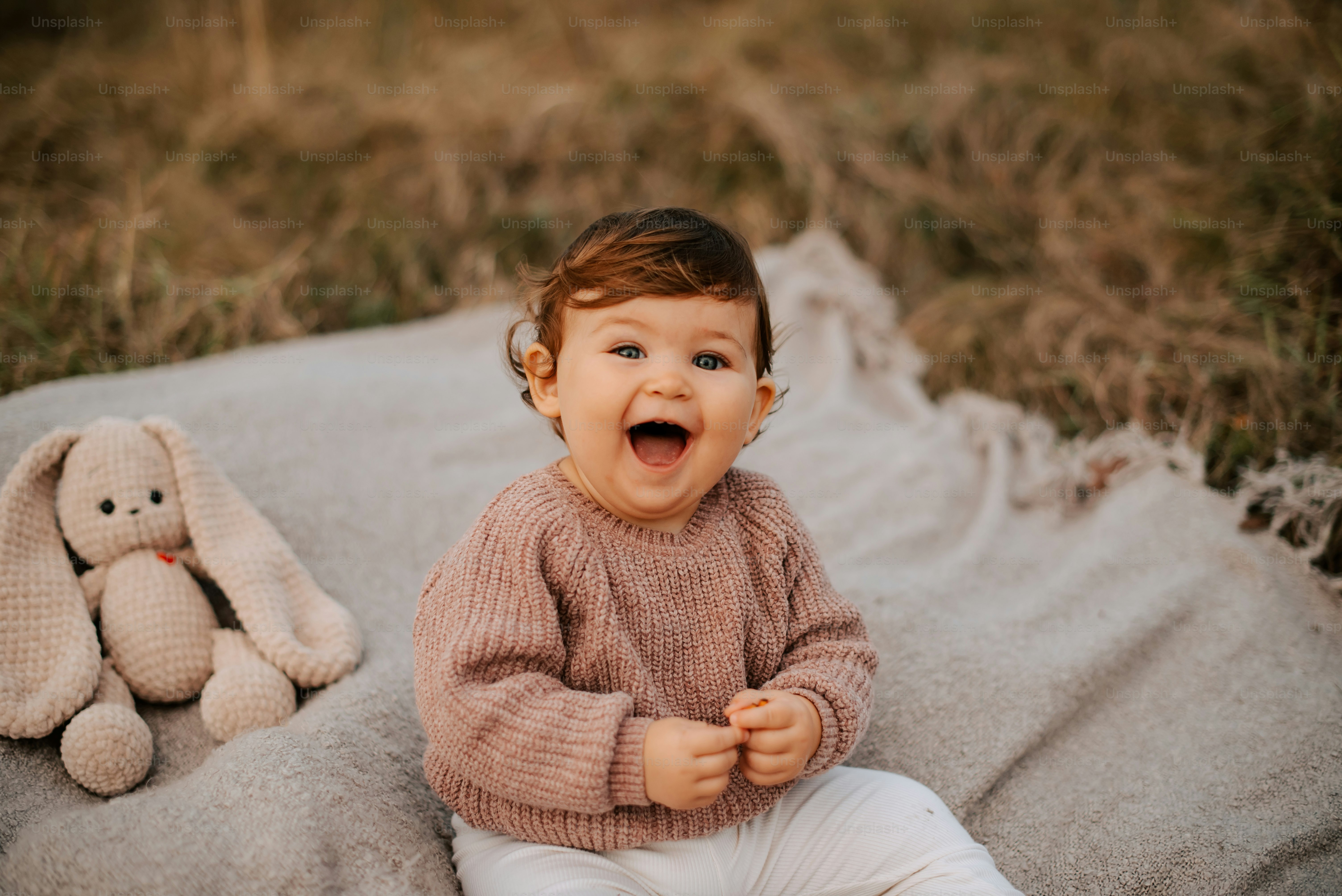 a baby sitting on a blanket next to a stuffed animal