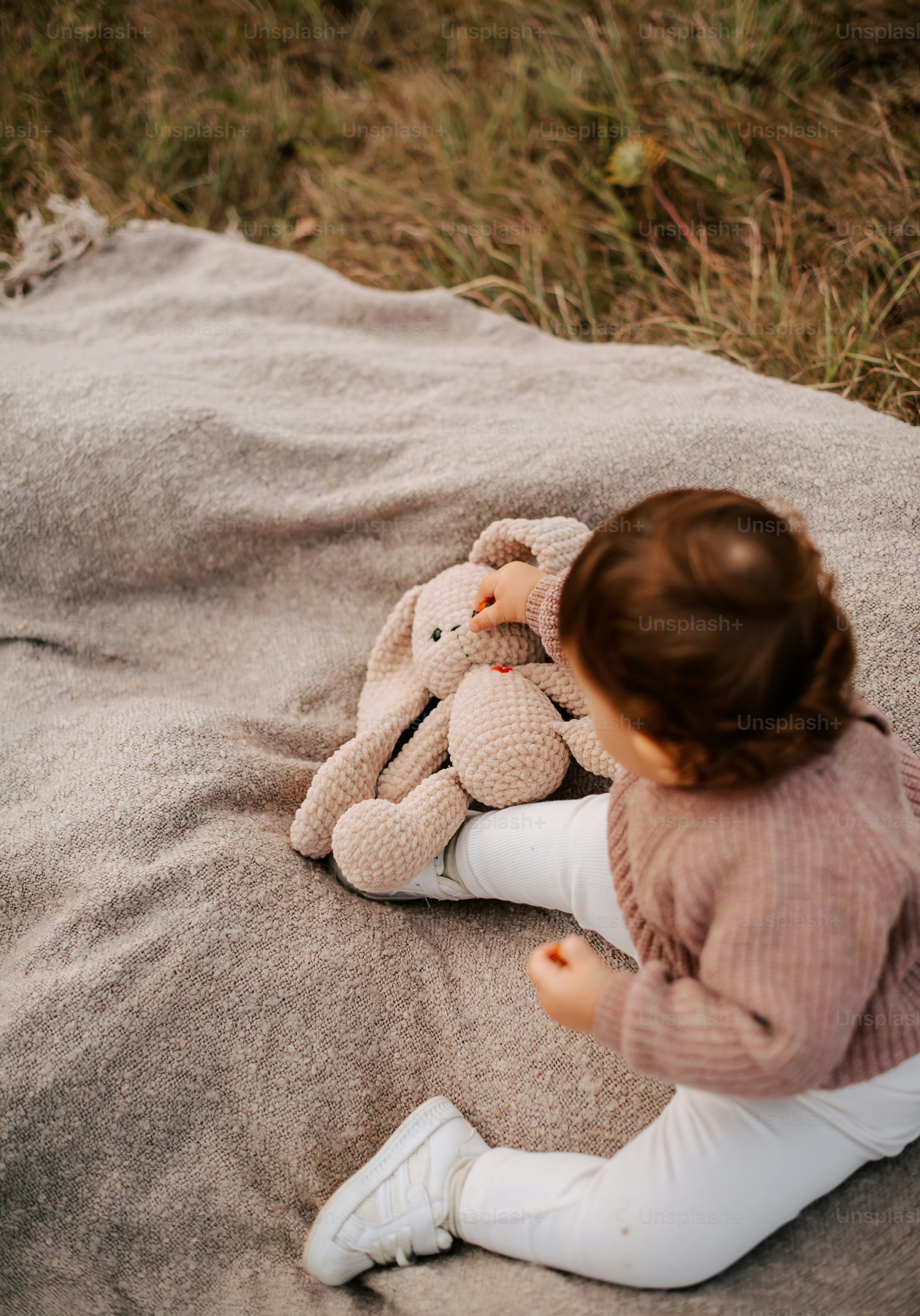 テディベアと毛布の上に座っている小さな女の子