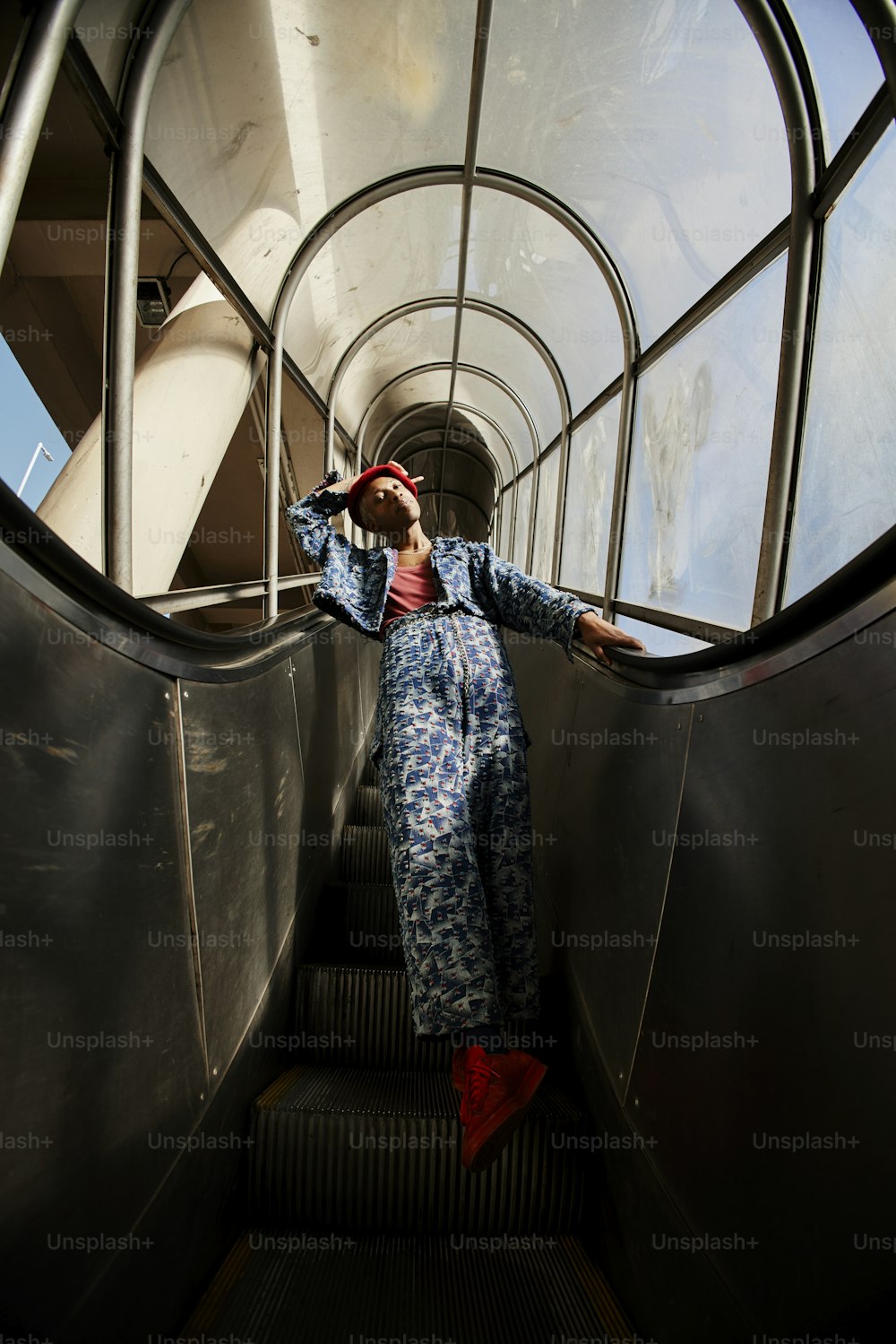 a woman in a blue jumpsuit is on an escalator