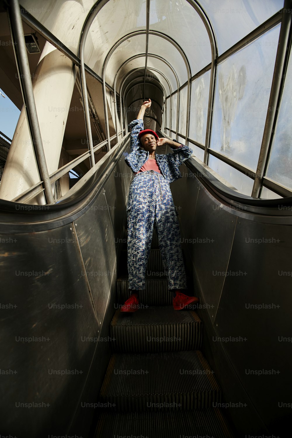 a man in a blue jumpsuit standing on an escalator