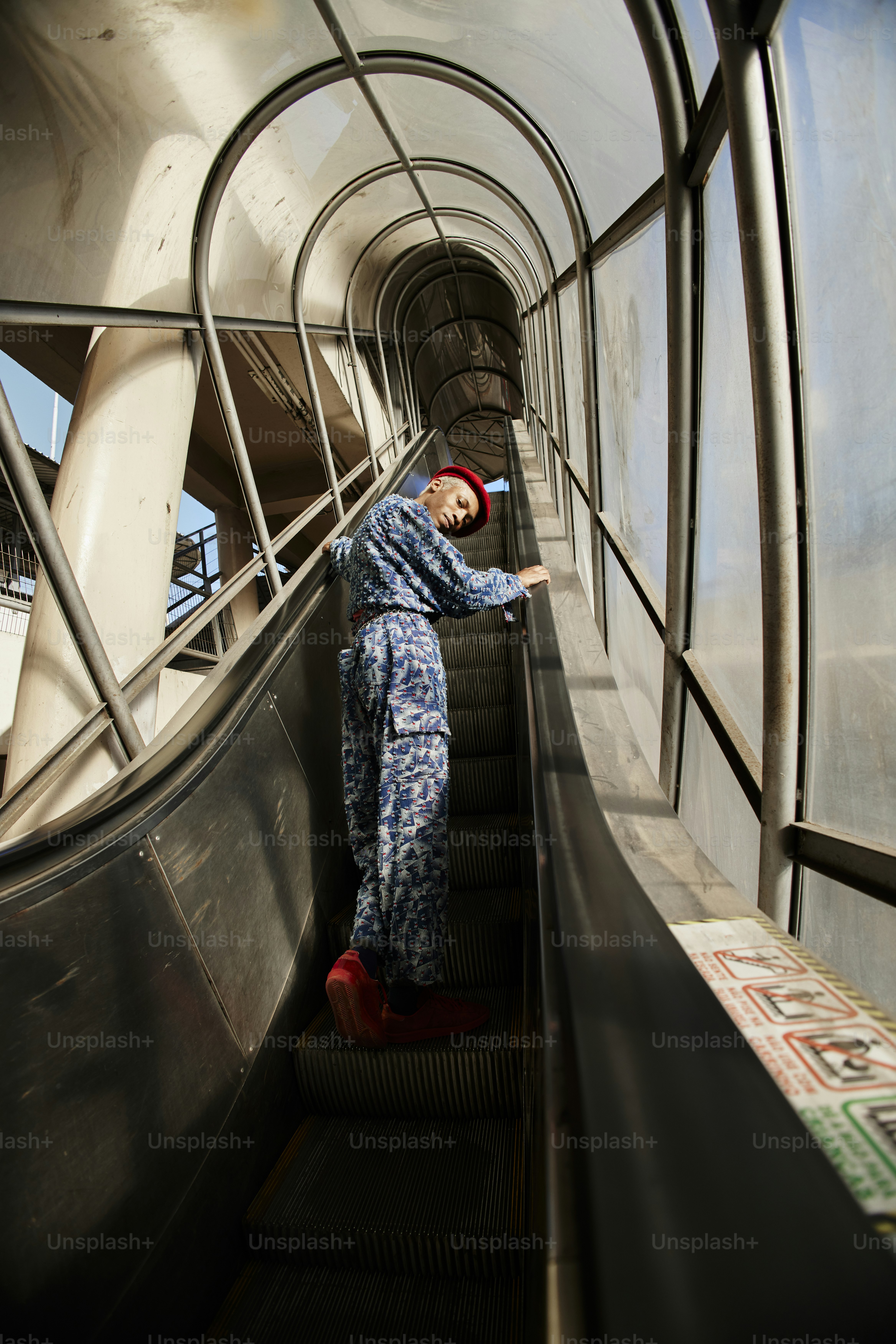 a man in blue jumpsuit riding down an escalator