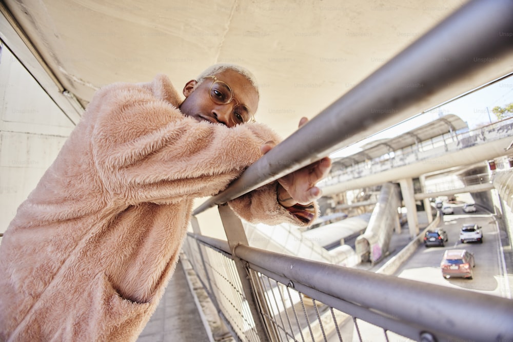 a man in a pink coat leaning on a railing