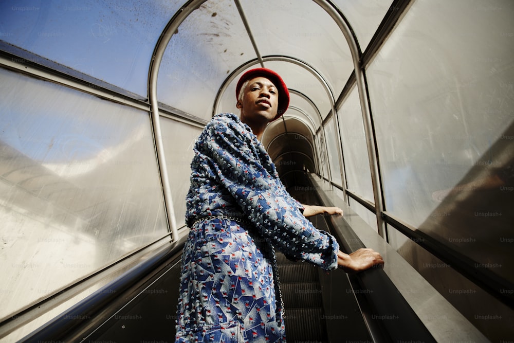 a woman in a blue dress and a red hat on an escalator