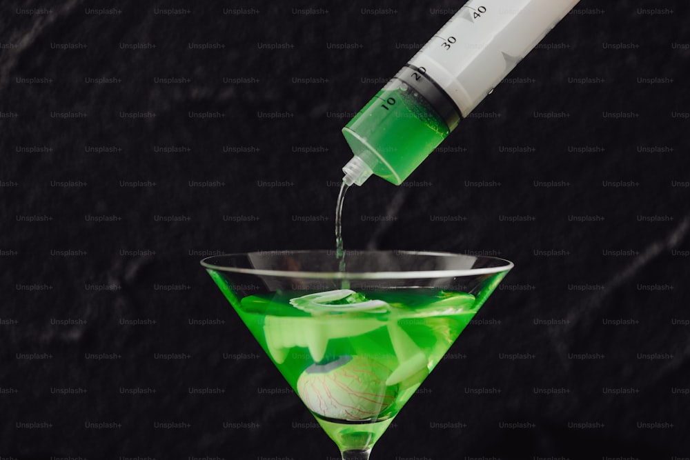 a green drink being poured into a martini glass