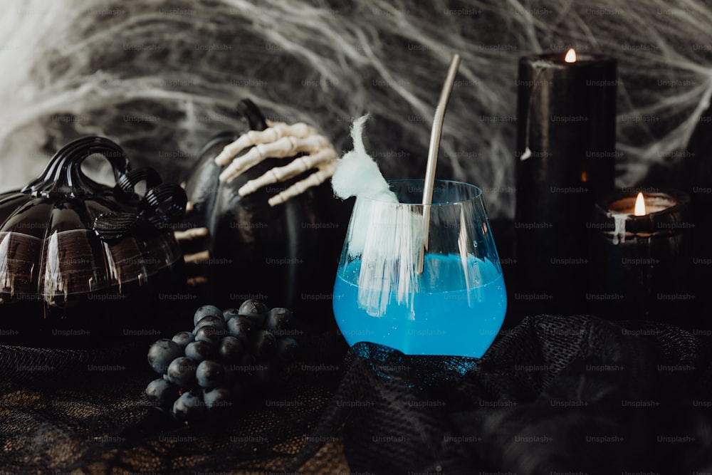 Um líquido azul em um vidro cercado por decorações de Halloween