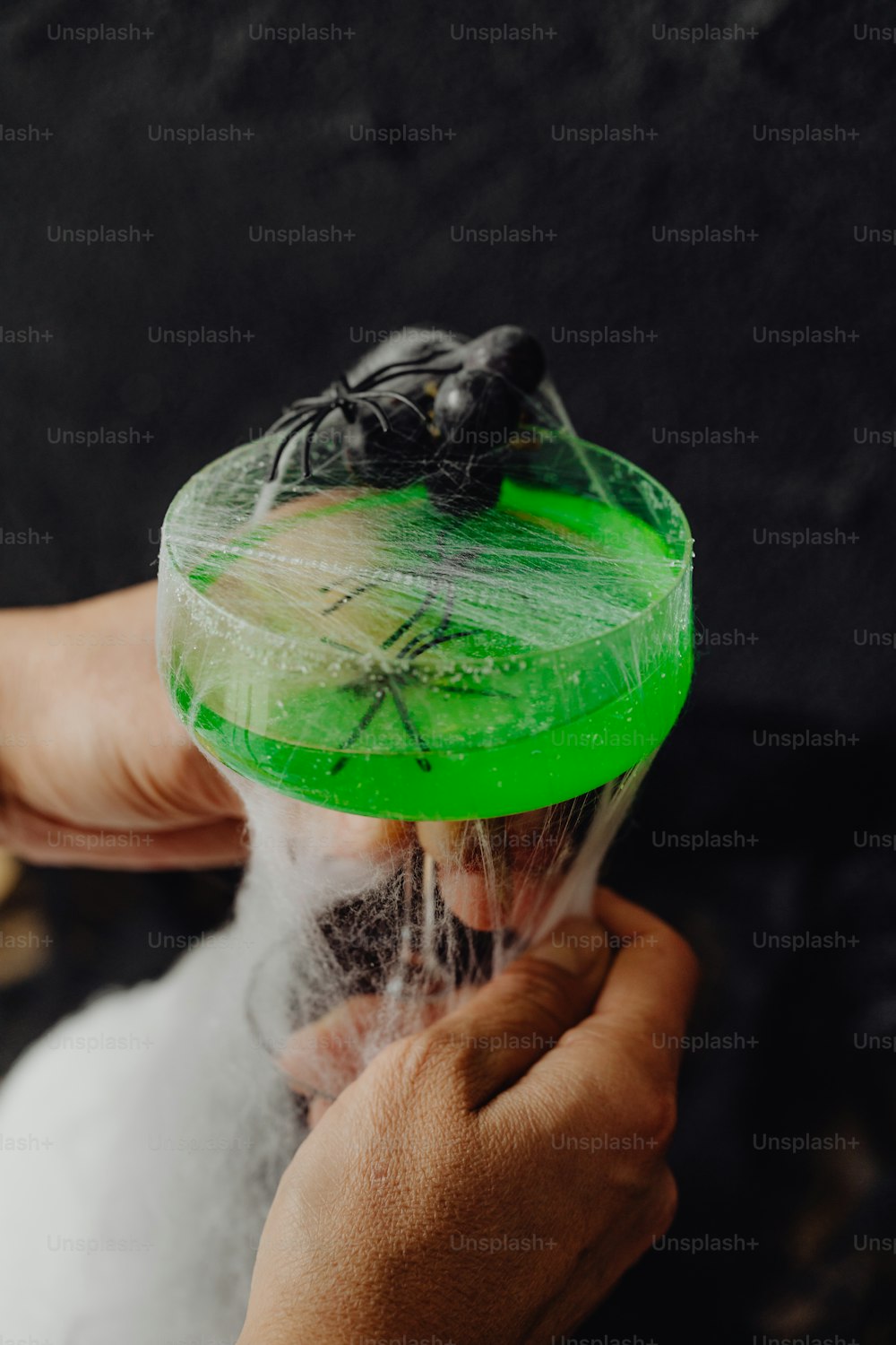 a person holding a plastic container with a spider on it