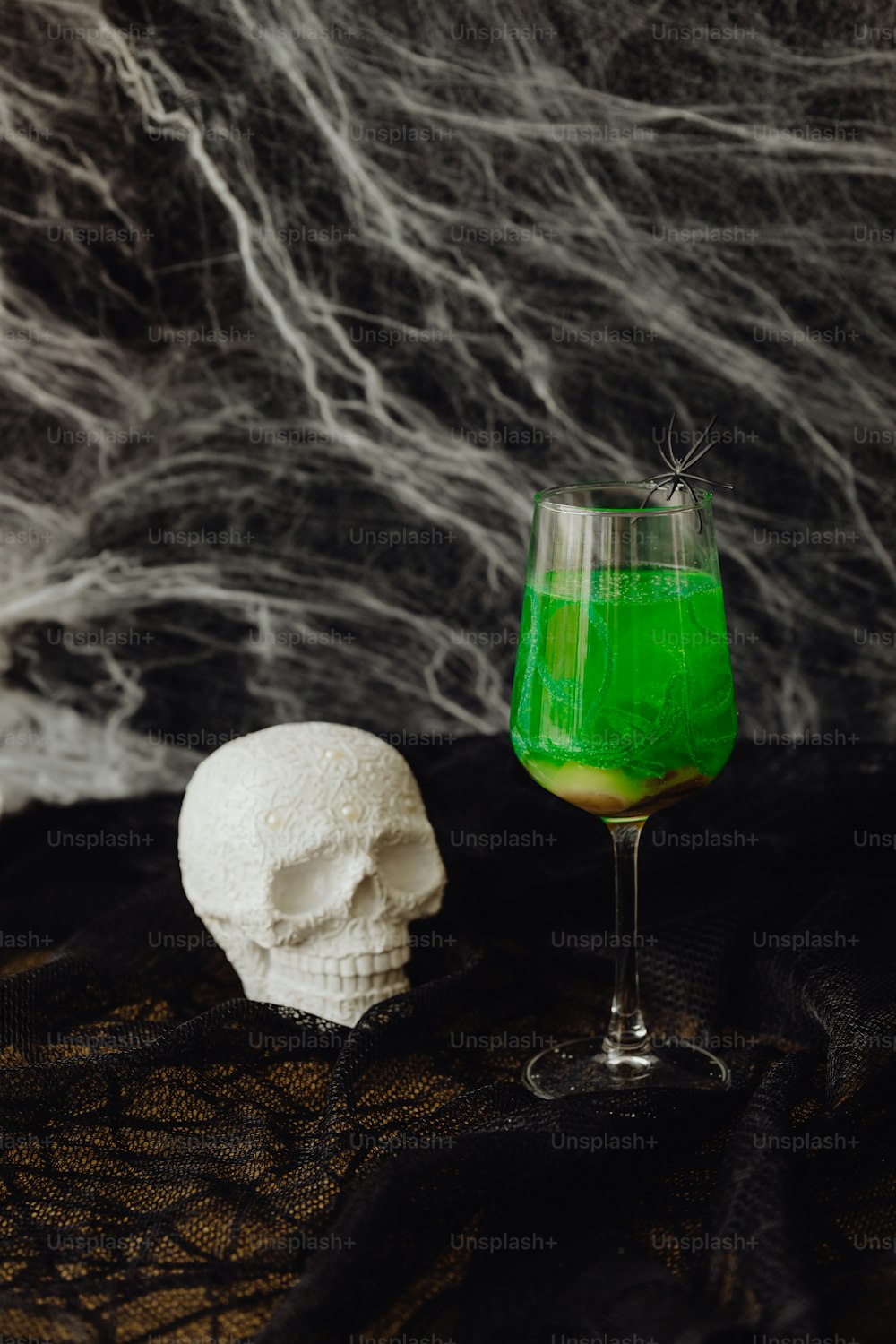 a green liquid in a glass next to a white skull