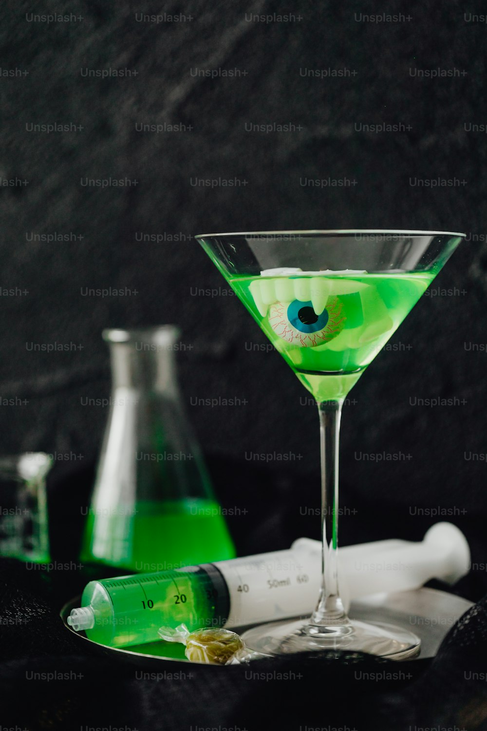 a green liquid in a glass next to a bottle