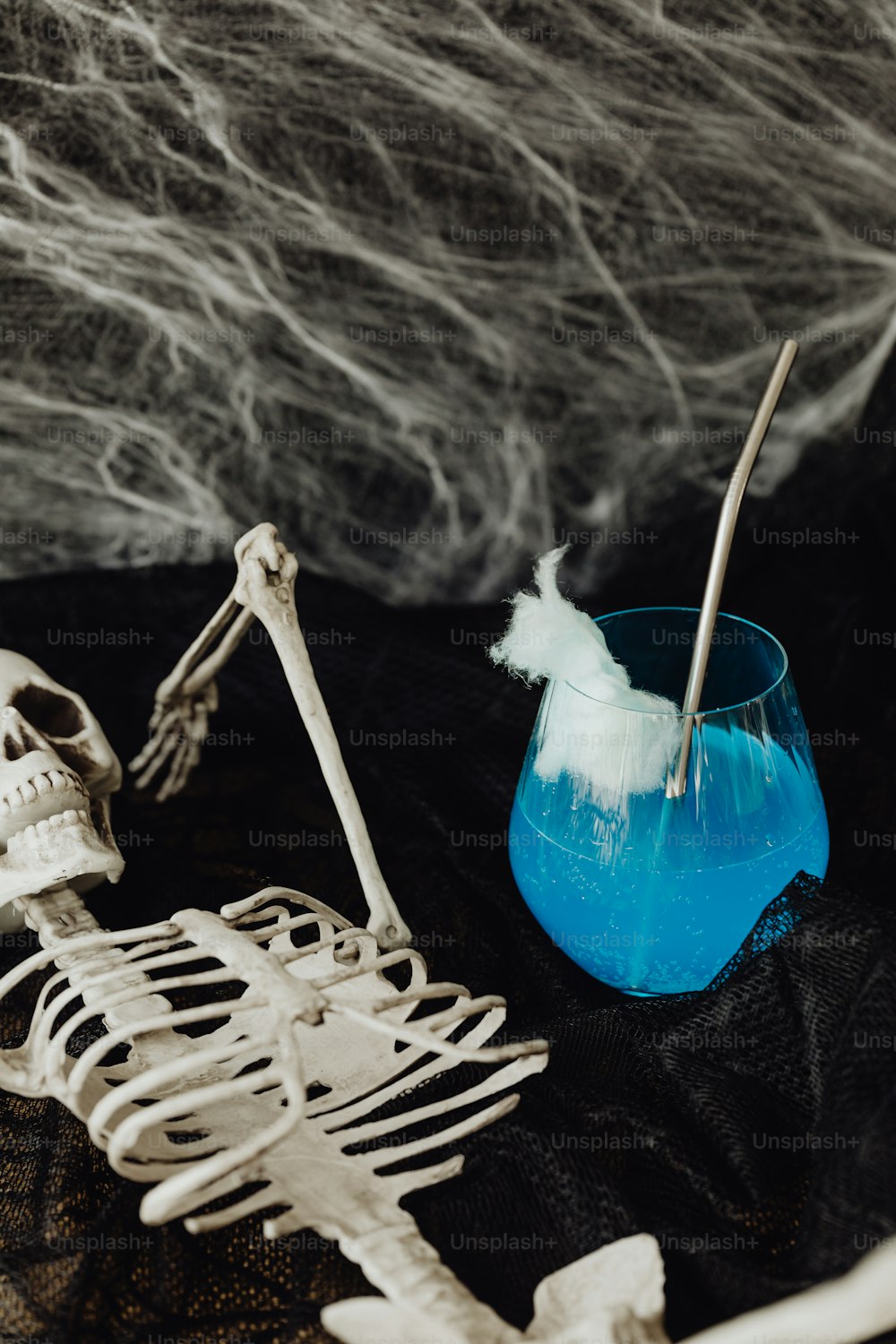 un squelette assis à côté d’une tasse bleue avec une brosse à dents dedans
