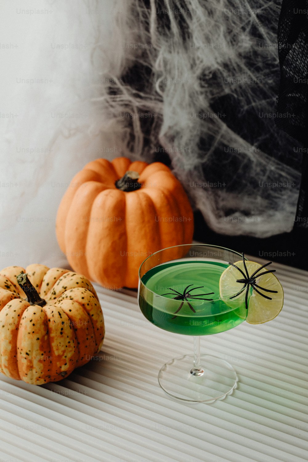 a glass of green liquid next to a pumpkin