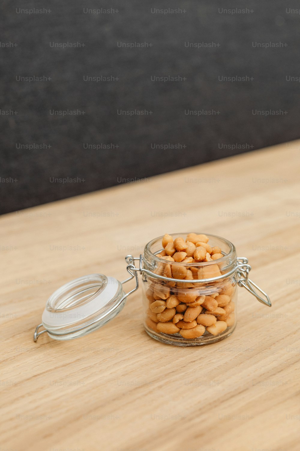 a glass jar filled with peanuts sitting on top of a wooden table