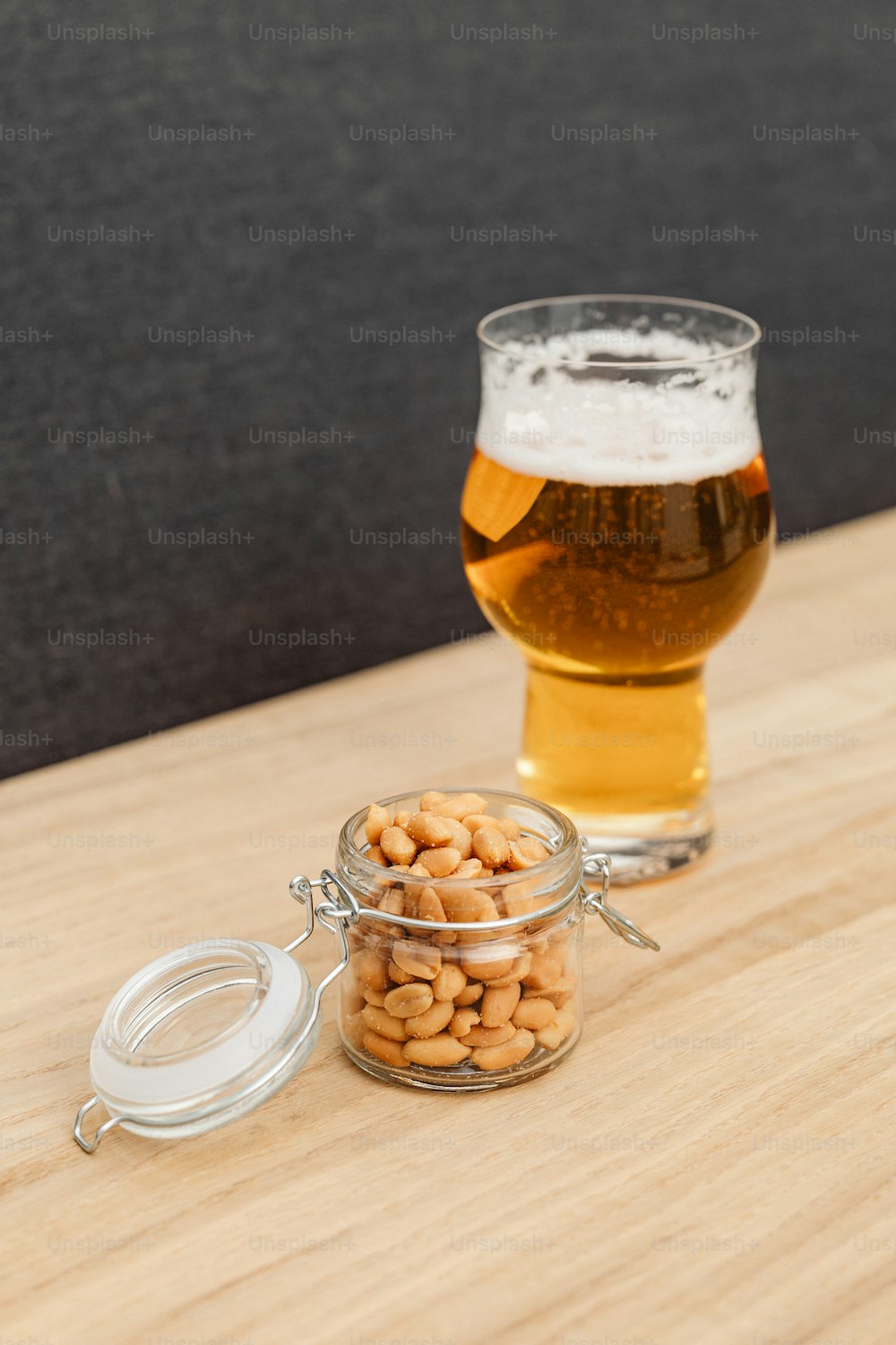 a glass of beer next to a jar of peanuts