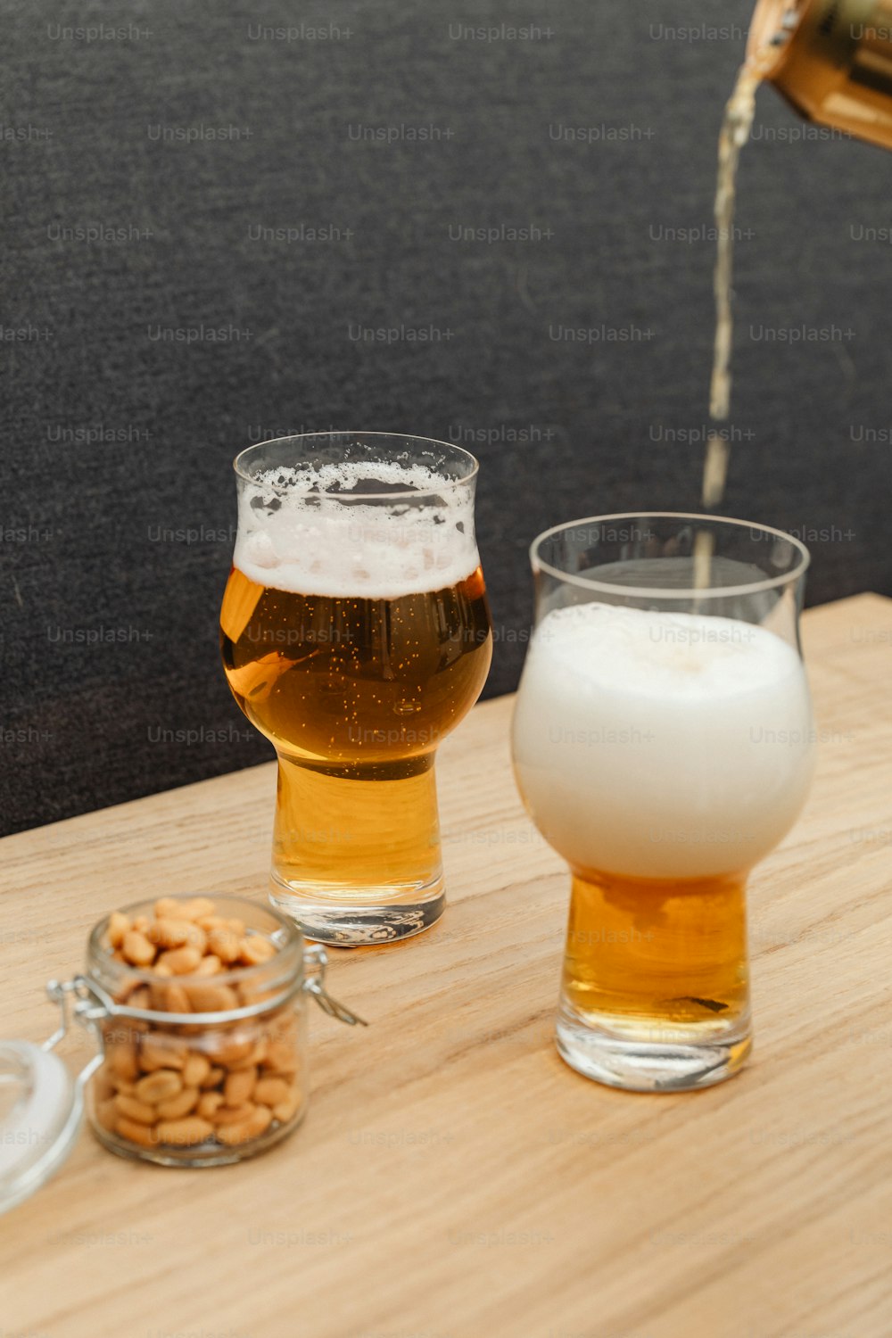 a wooden table topped with two glasses of beer