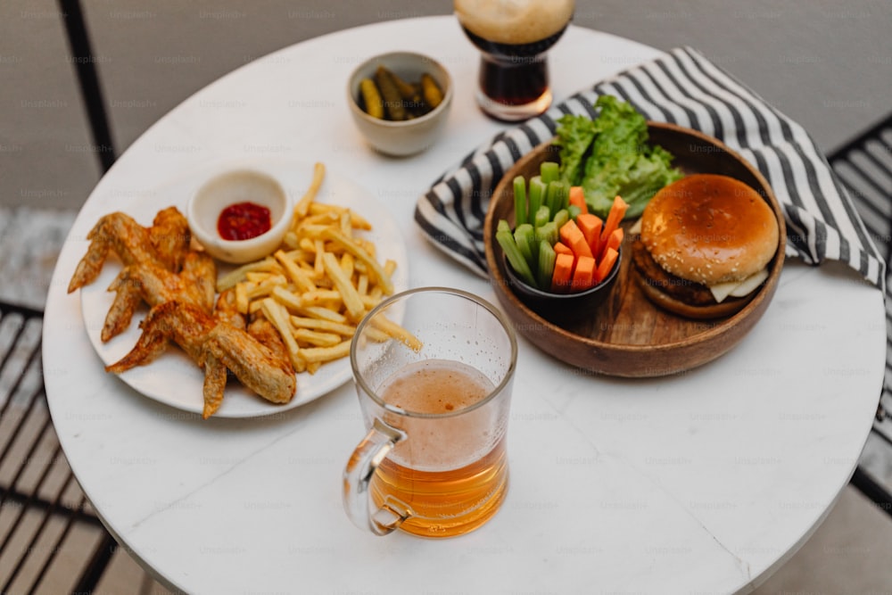 a white table topped with a plate of food and a glass of beer
