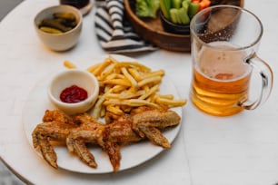 a white plate topped with french fries next to a glass of beer