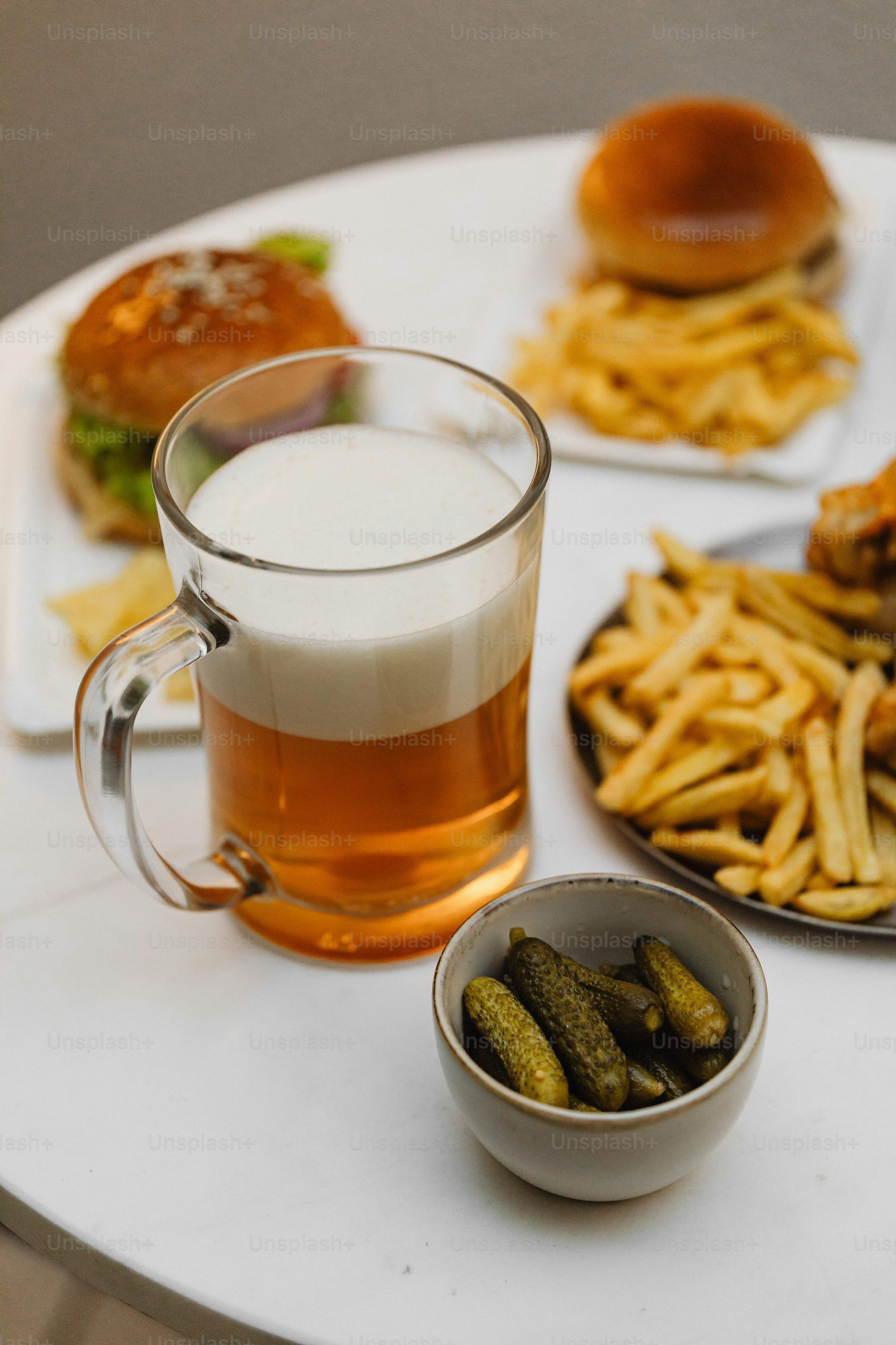 A table topped with plates of food and a cup of beer photo – Food Image ...