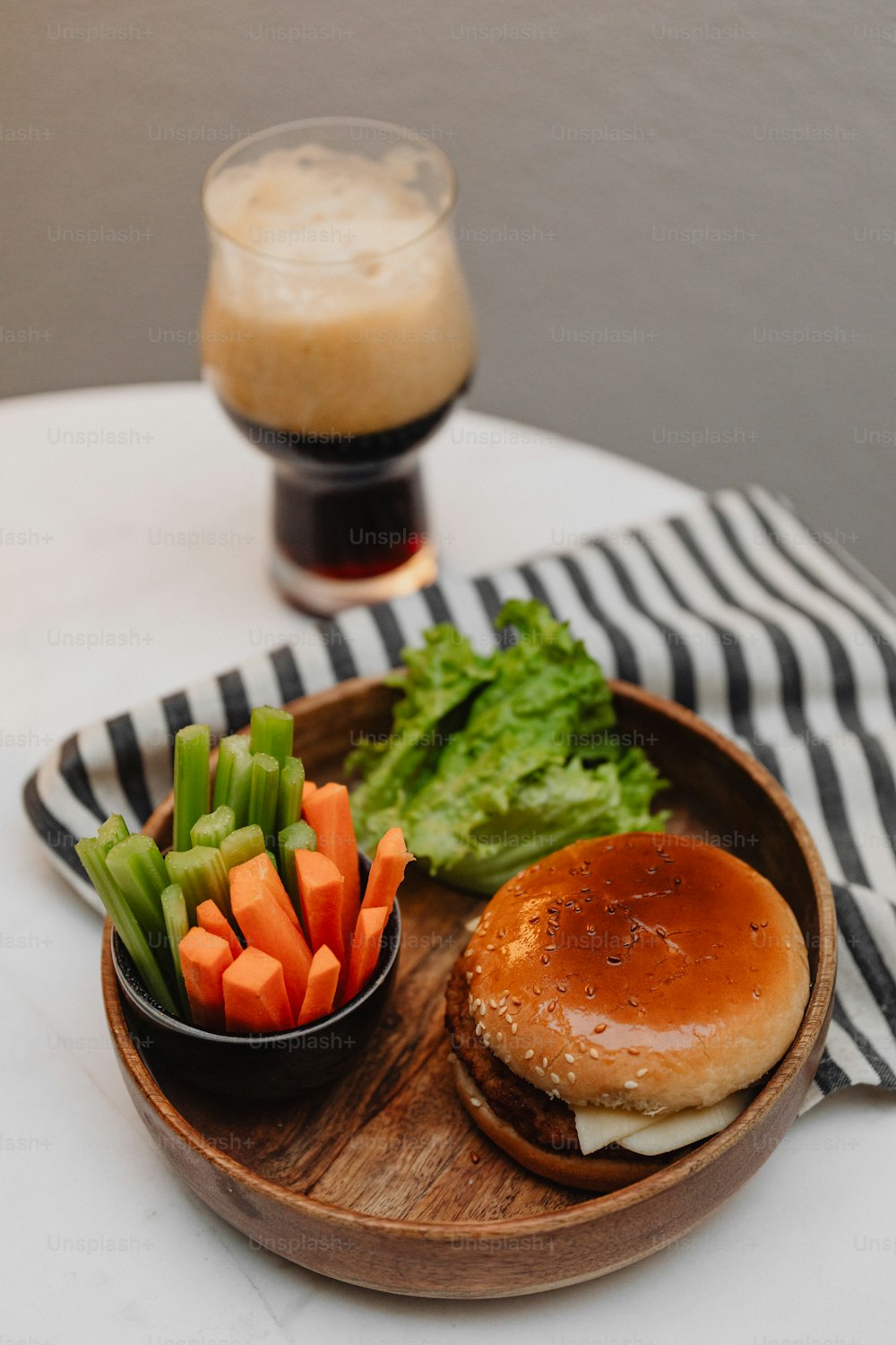 a plate with a burger, carrots and celery on it