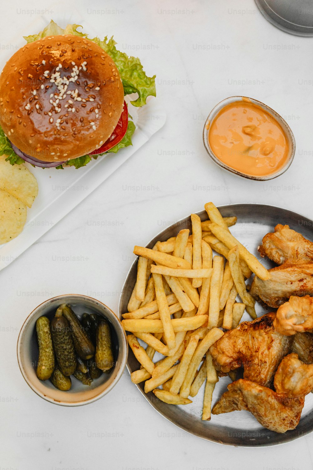 a plate of fries, pickles, and a burger on a table