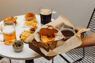 ein Tisch mit einem Korb mit Essen neben einem Becher Bier