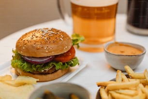 a hamburger and fries on a plate with a glass of beer